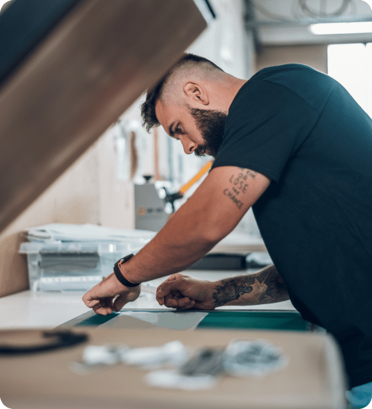 A man carefully performing the embroidery process on fabric.